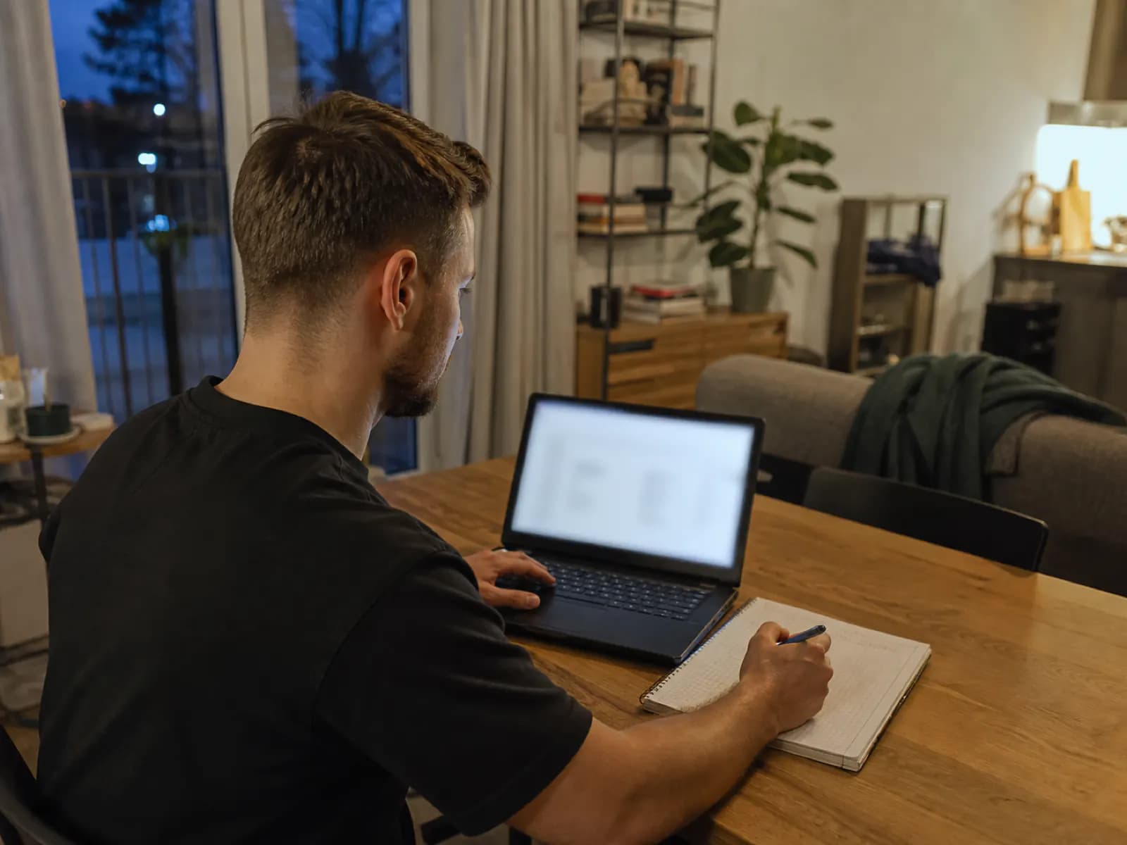 Trener pracuje wieczorem przy laptopie i notesie w domu