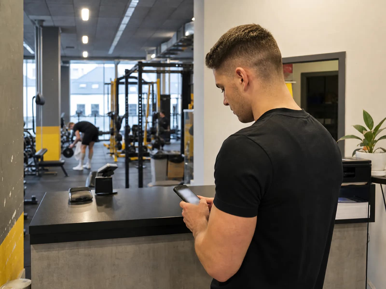 Trener sprawdza telefon przy recepcji siłowni