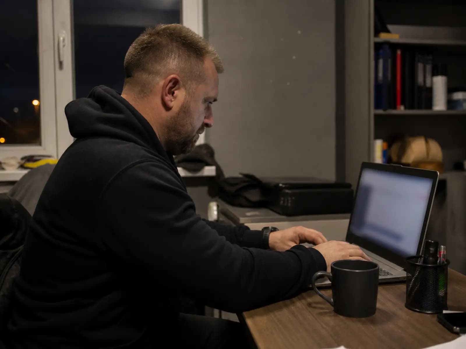 Trener pracuje wieczorem przy laptopie w biurze klubu